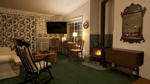 A cozy living room with a fireplace, a television, and a dining area. - Private Cottage “Wild Rose” (Julian)