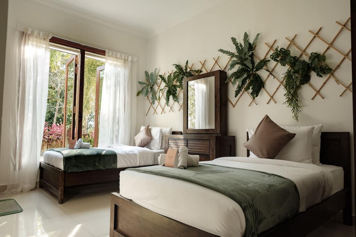 A hotel room with two beds, a large mirror, and a wall-mounted plant display.
