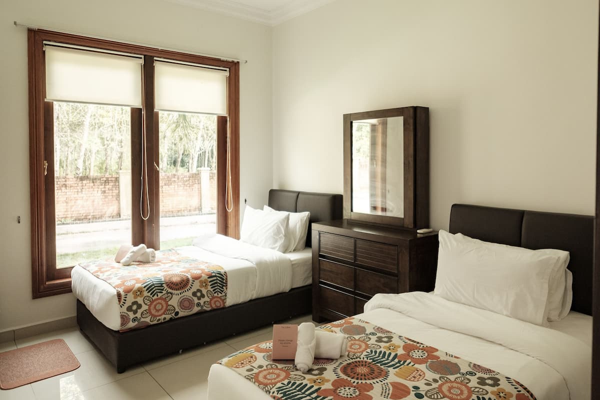 A hotel room with two beds, a wooden dresser, a mirror, and a view of the outside.