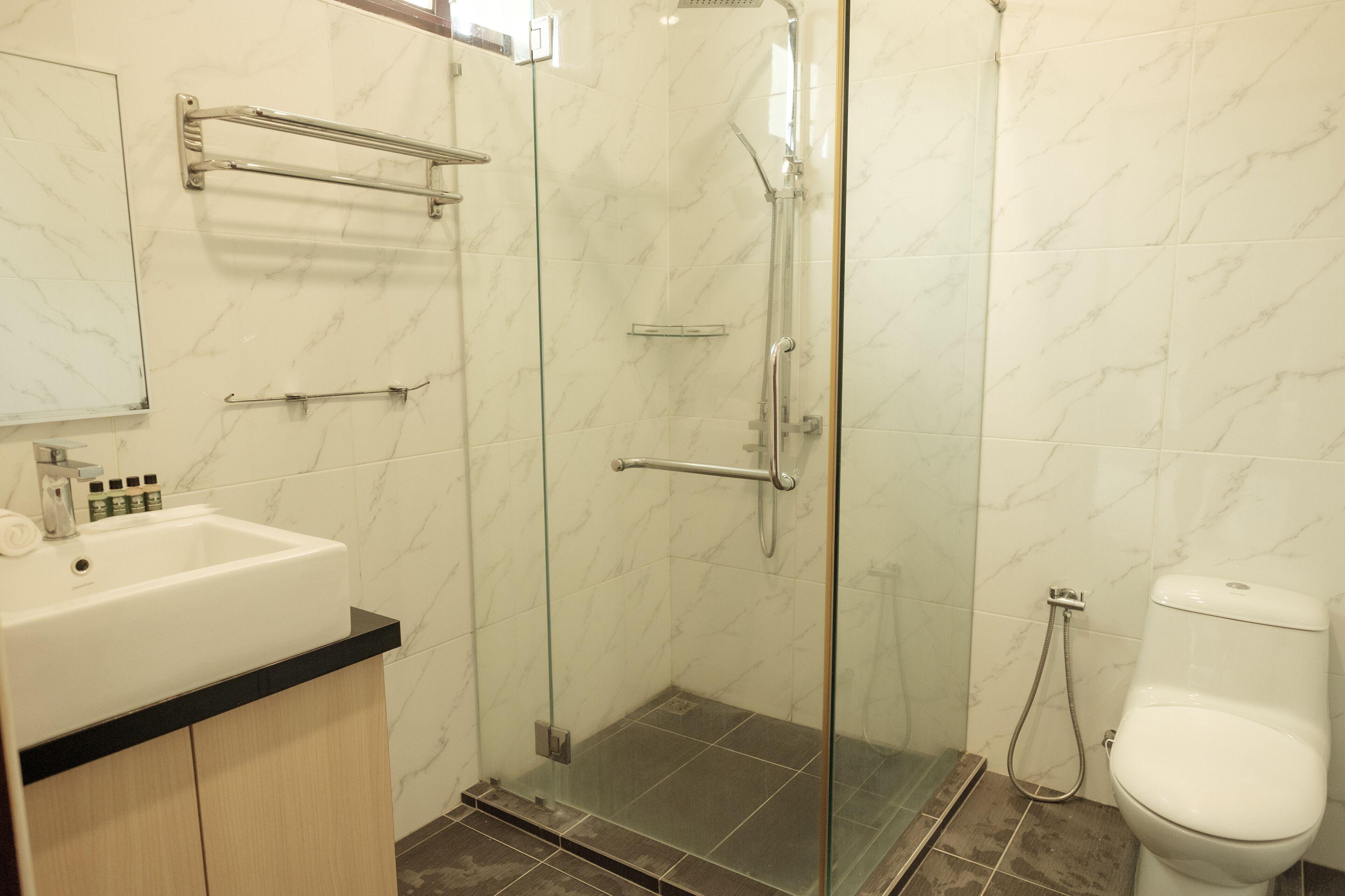 Ein Badezimmer mit Duschkabine, Waschbecken in Weiß mit schwarzer Ablage und Toilette.