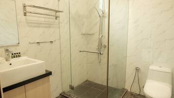 Ein Badezimmer mit Duschkabine, Waschbecken in Weiß mit schwarzer Ablage und Toilette.