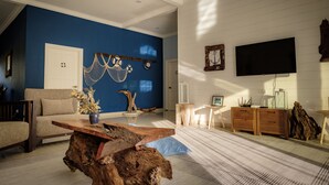 Ein Wohnzimmer mit blauer Akzentwand, einem Holztisch, einer Couch und einem an der Wand montierten Fernseher.