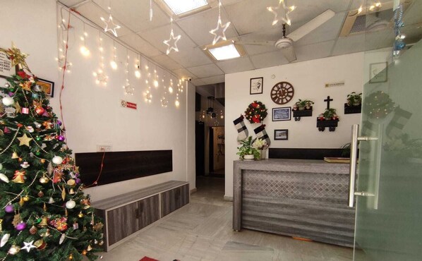 A reception area with a Christmas tree, a clock, and a wall-mounted cross. - Hope Inn (Kolkata)