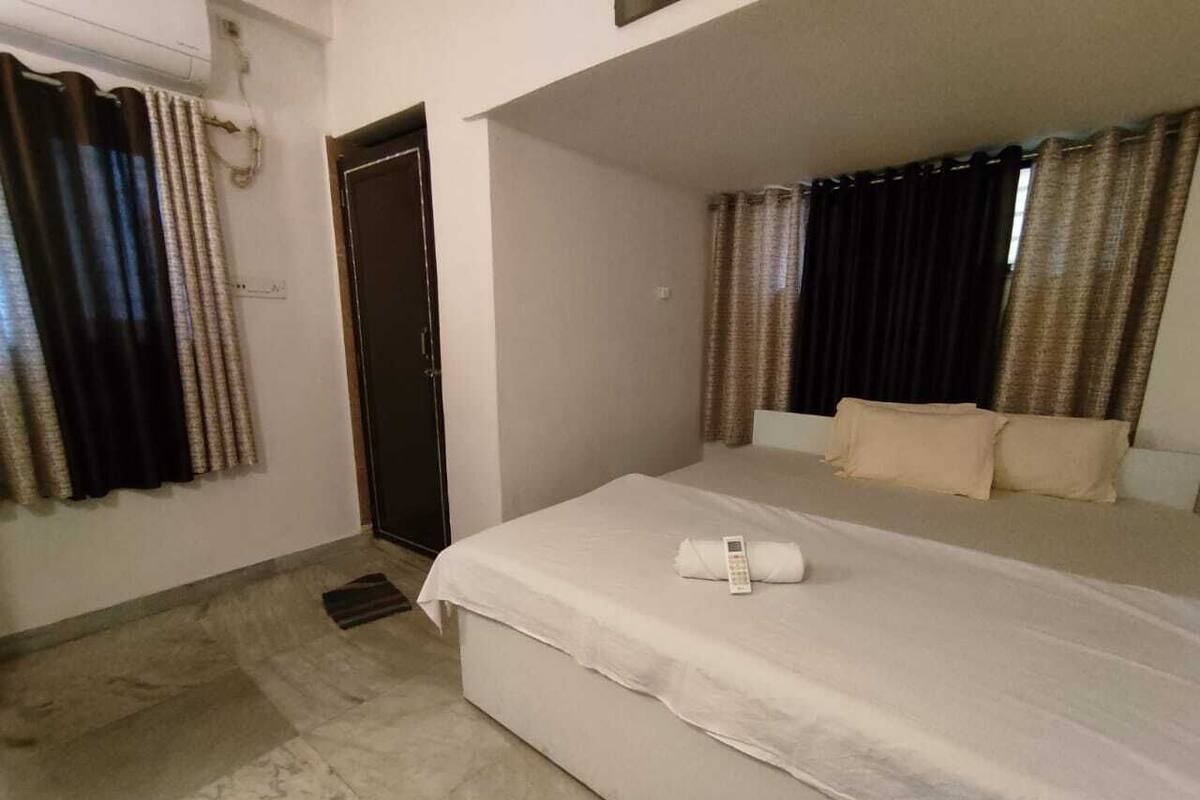 A hotel room with a bed, a door, and curtains.