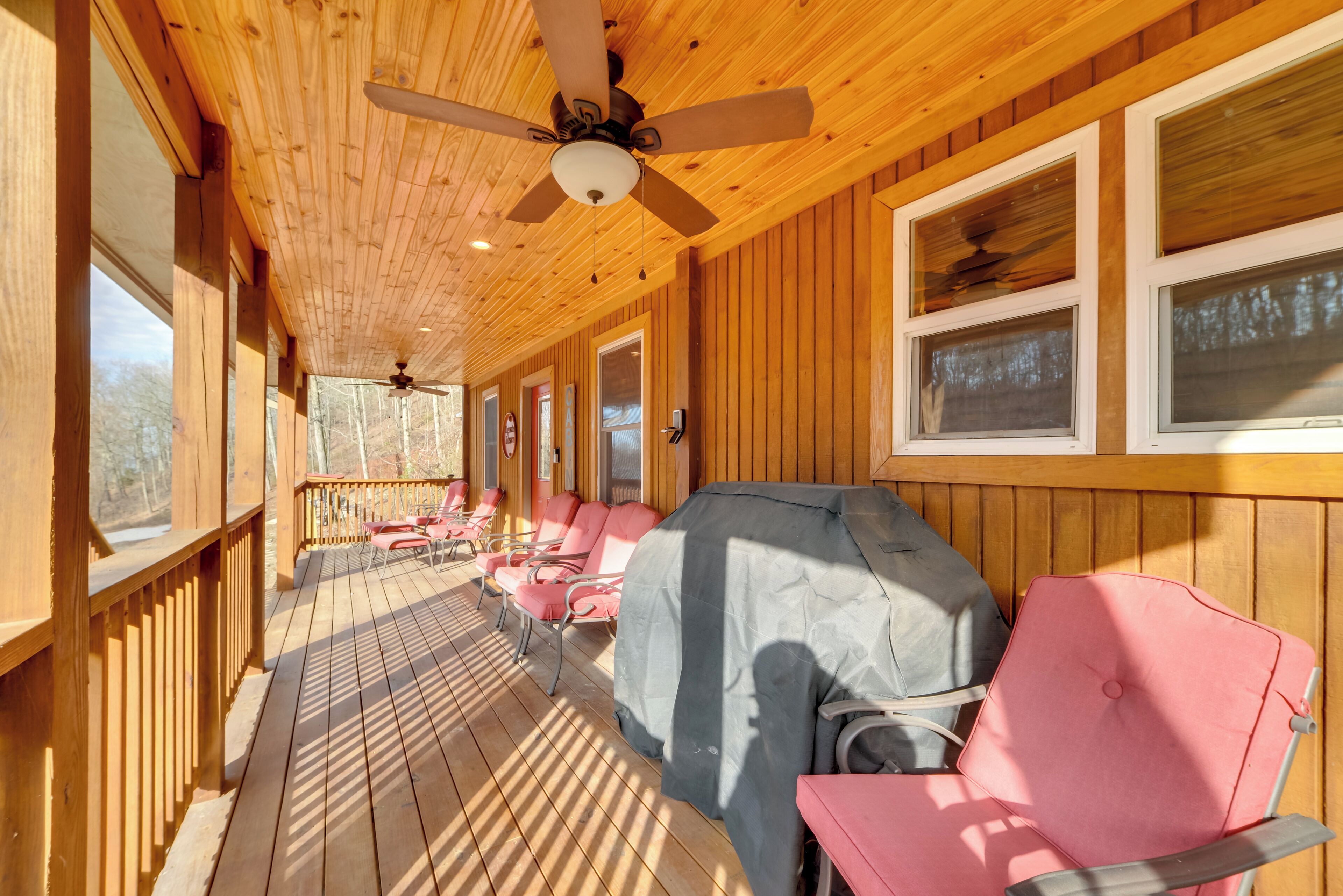 Une terrasse couverte avec un plancher en bois, un ventilateur de plafond et un barbecue.