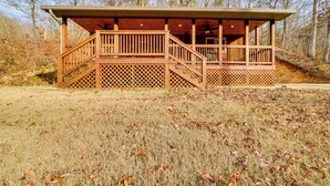 A wooden cabin with a covered porch and a staircase leading to an upper deck.