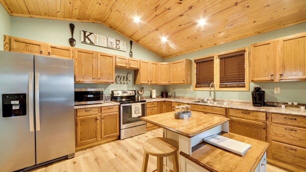 A kitchen with wooden cabinets, stainless steel appliances, and a wooden ceiling.