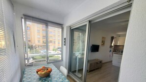 A small dining area with a table set for two, a bowl of fruit, and a sliding glass door leading to a kitchen. - Renovated studio close to the beach of Sainte Asile in Pin Rolland (ST MANDRIER SUR MER)