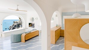 Een modern interieur met uitzicht op zee, een houten bank en een badkamer met een houten wastafelmeubel.