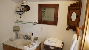 A bathroom with a sink, mirror, towel rack, and a small wooden cabinet. - Private Cottage “Storybook Barn” (Julian)