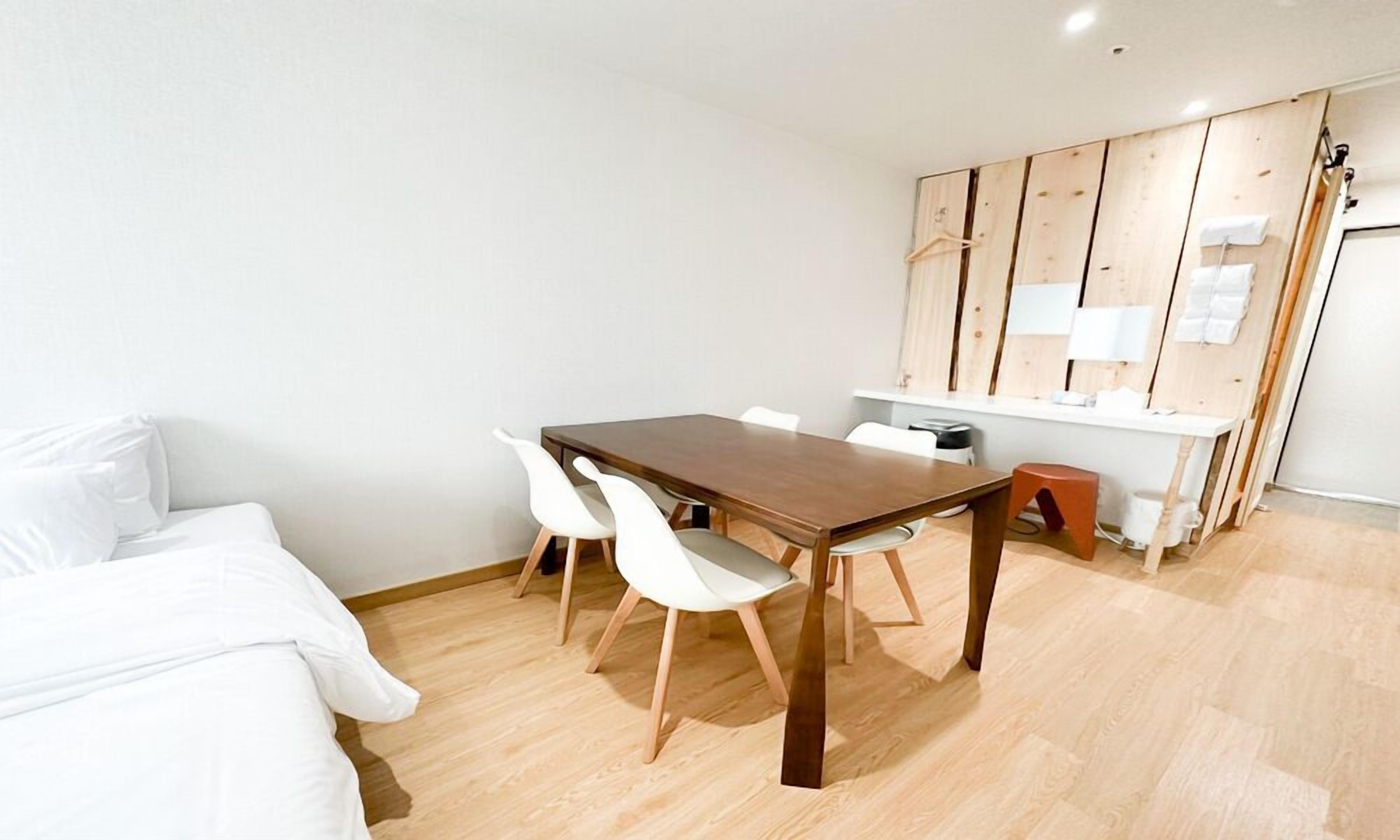 Une pièce moderne et minimaliste, avec une table à manger en bois, des chaises blanches et un canapé blanc.