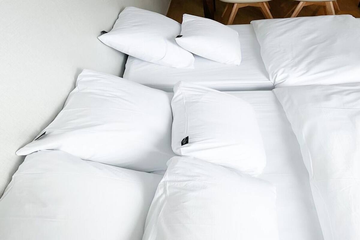 A neatly made bed with white bedding and pillows.