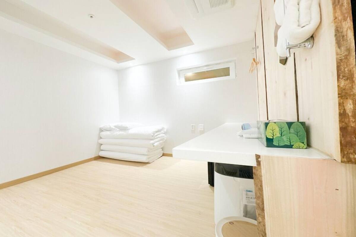 A clean, minimalist bathroom with a wooden floor, a white sink, and a towel stack.