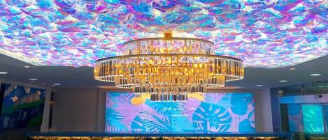 Un candelabro con diseño escalonado, una pared de piedra con fuente de agua y un techo con exhibición de luces de colores.