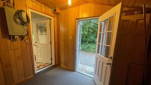 A wooden interior hallway with two open doors leading outside.