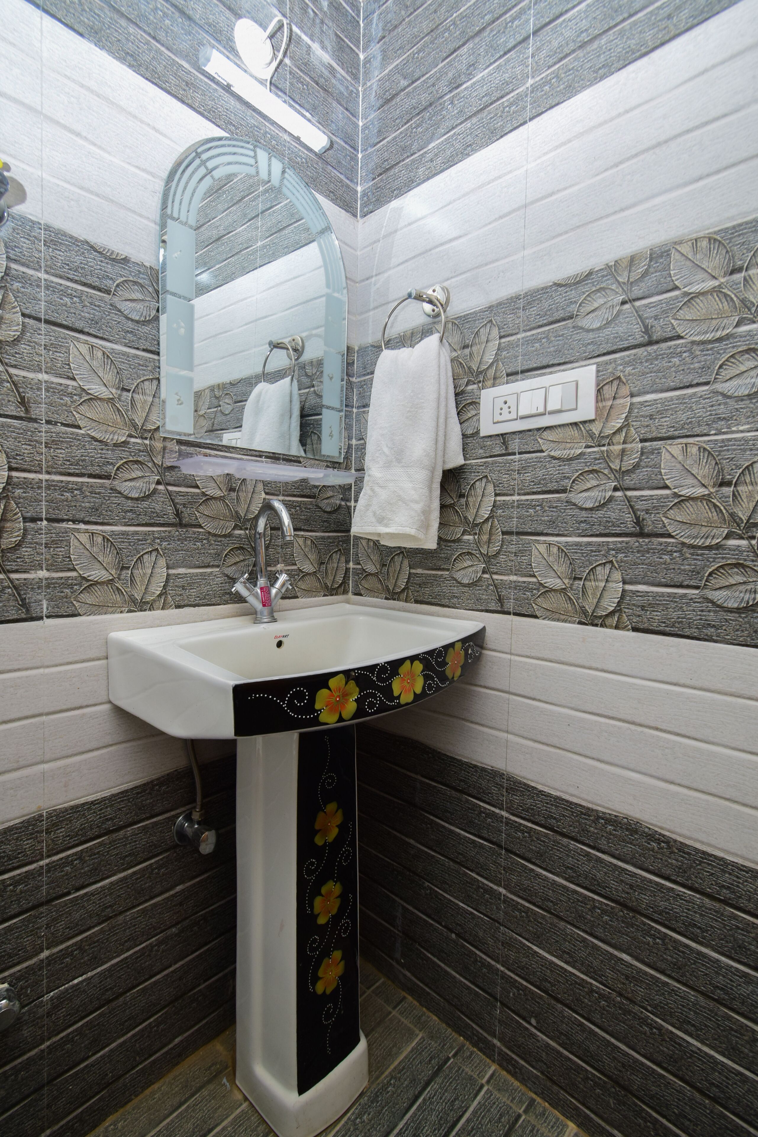 Une salle de bain avec un lavabo blanc, un miroir et une serviette accrochée au mur.