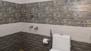 Un baño con inodoro blanco, calentador de agua instalado en la pared y salpicadero de azulejos estampados.