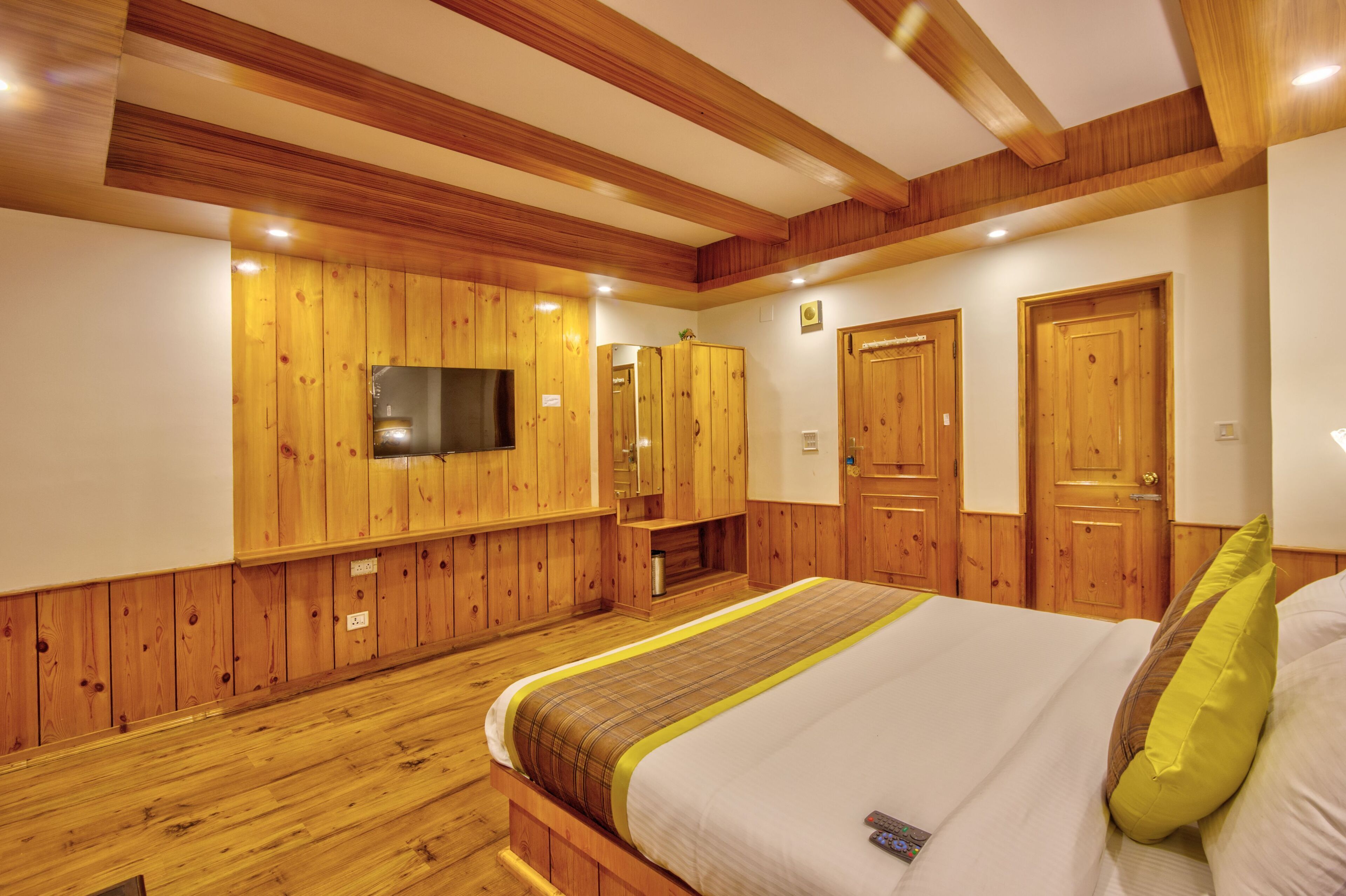 Un dormitorio con paneles de madera, una cama, un televisor y dos puertas.