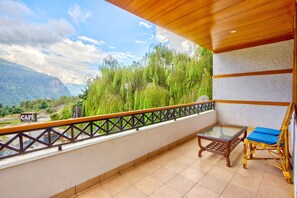 A balcony with a view of a mountainous landscape, a table, and two chairs. - Solang Cottage By Snow City Farm (Manali)