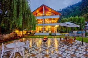 A two-story building with a wooden facade, outdoor seating area with chairs and a table, and a fire pit.