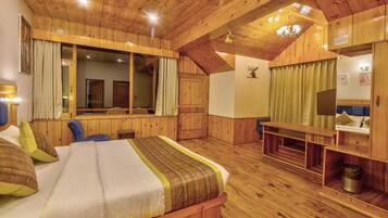 A wooden-floored bedroom with a bed, a desk, and a mirror.