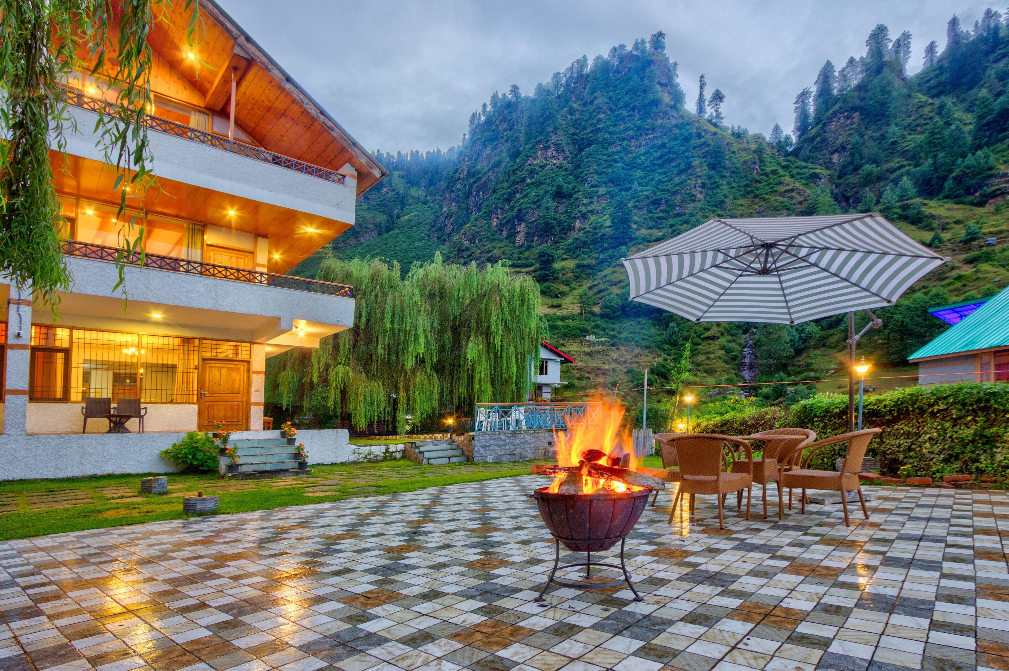 A checkered outdoor patio with a fire pit, outdoor seating, and a mountain backdrop.