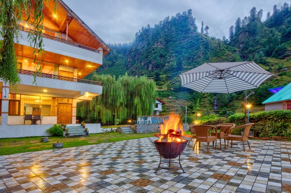 A checkered outdoor patio with a fire pit, outdoor seating, and a mountain backdrop.