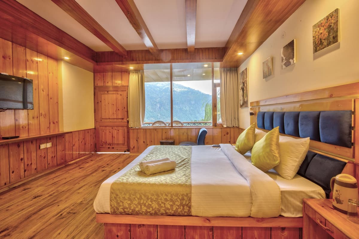 Un dormitorio de estilo cabaña de madera con una cama grande, un televisor y una ventana con vistas a la montaña.