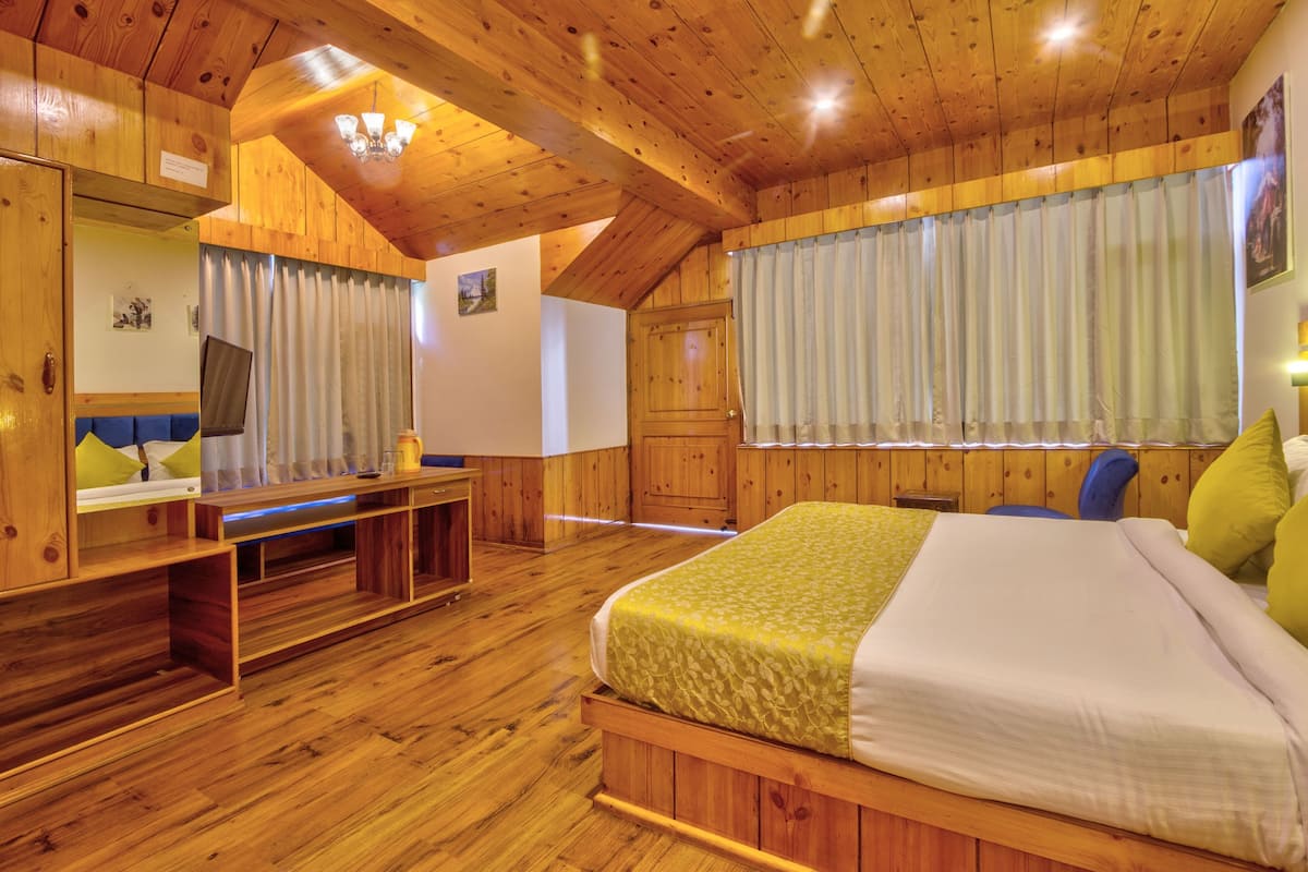 Un dormitorio con suelo de madera, una cama, un escritorio y una silla.