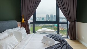 Ein Hotelzimmer mit großem Fenster, einem Bett mit weißer Bettwäsche und Blick auf eine Stadtlandschaft.