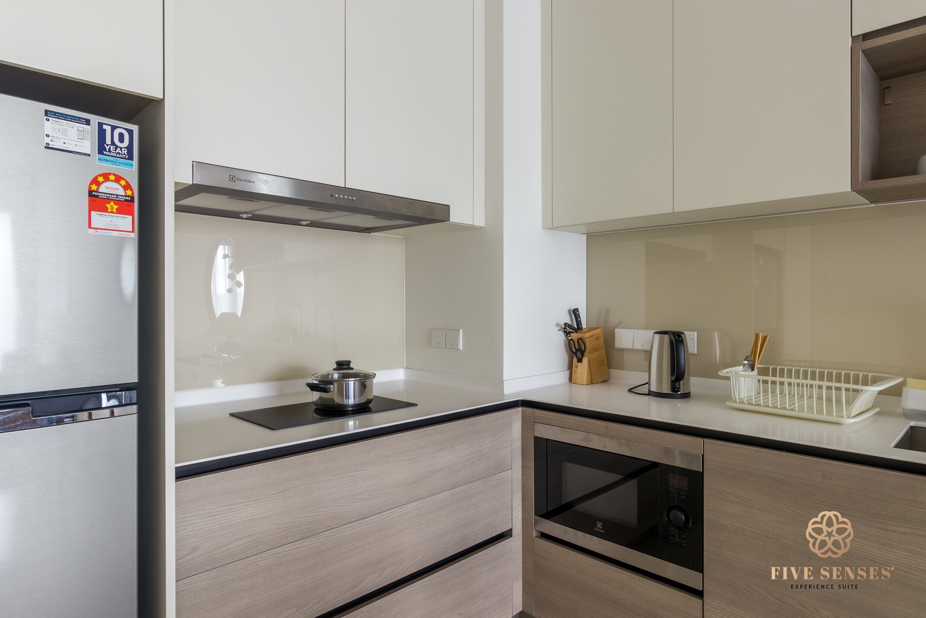 Una cocina moderna con un refrigerador de acero inoxidable, un horno empotrado y un microondas.