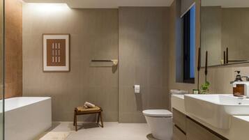 Un baño moderno con una bañera grande, dos lavamanos, un inodoro y una zona de ducha.