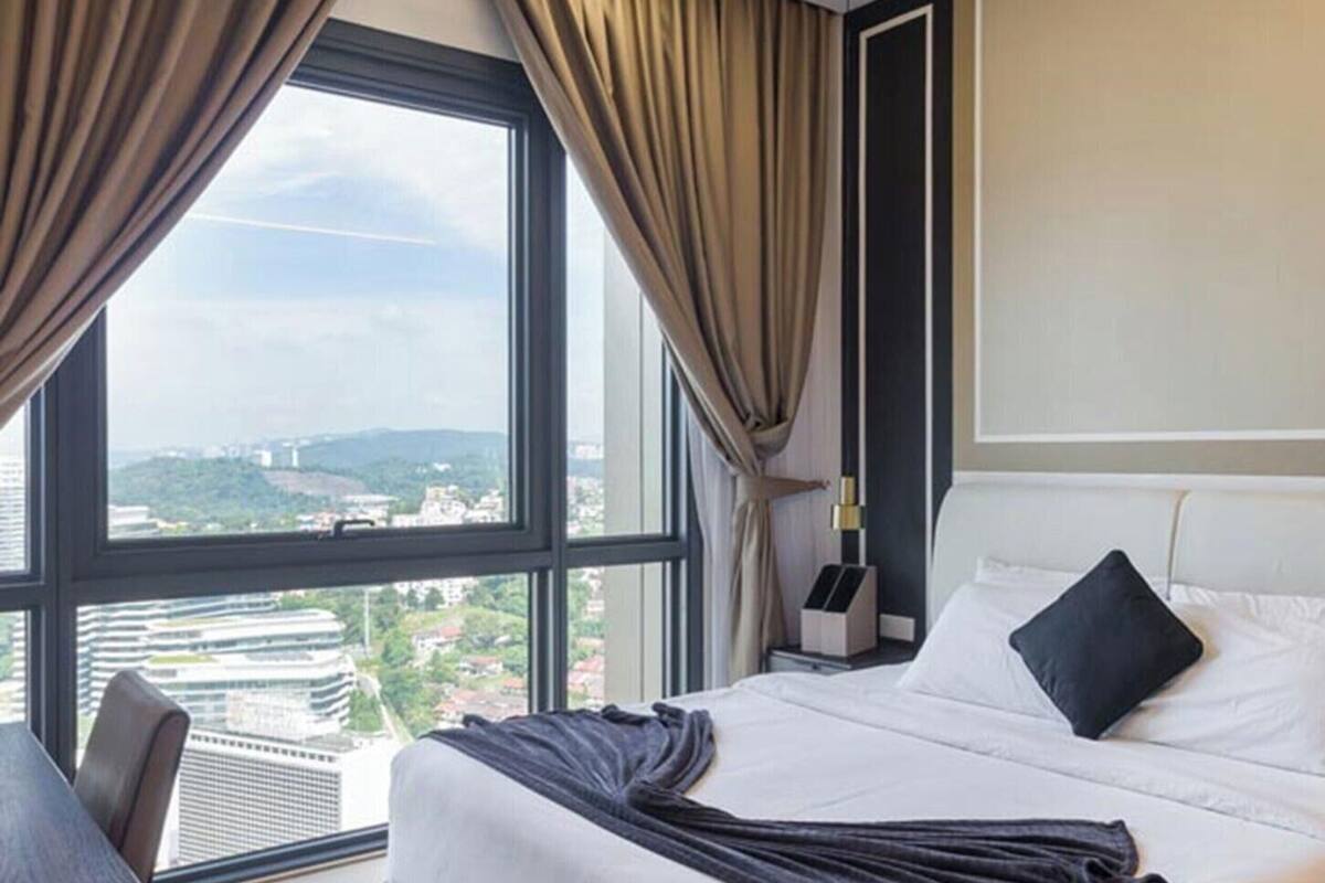 Quarto de hotel com uma janela grande, uma cama, uma mesa de cabeceira e uma cadeira.