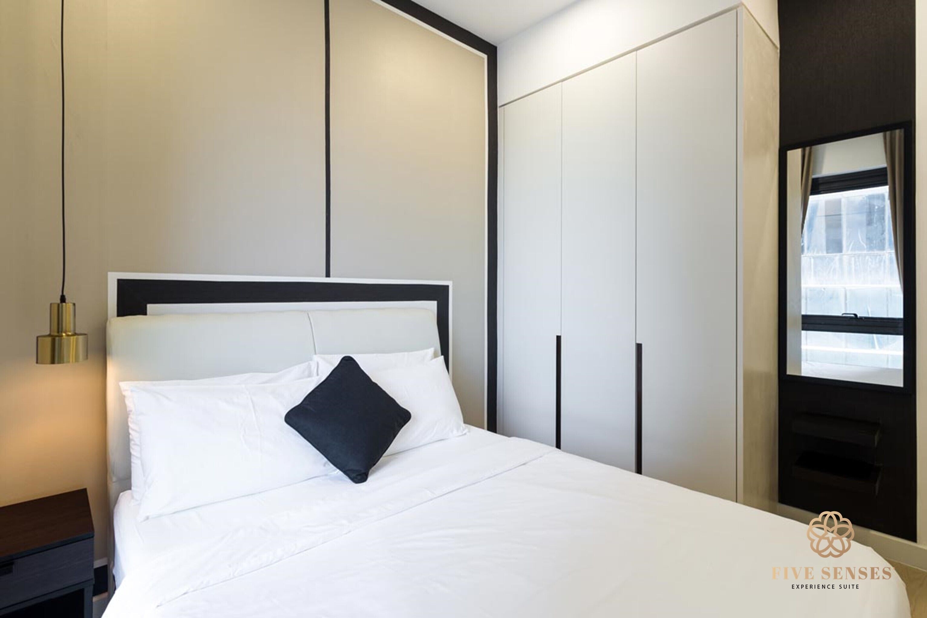 A modern hotel room with a neatly made bed, a bedside table, and a wardrobe with sliding doors.