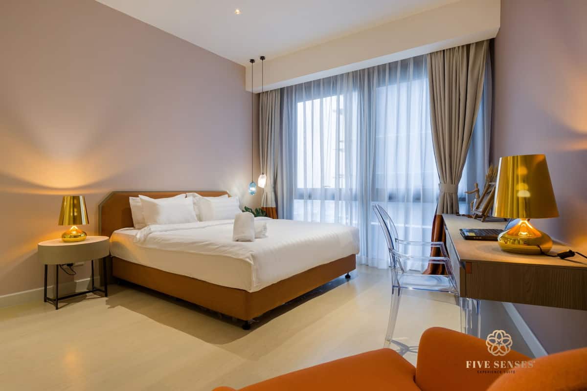 Quarto de hotel moderno com uma cama grande, uma escrivaninha e uma cadeira.