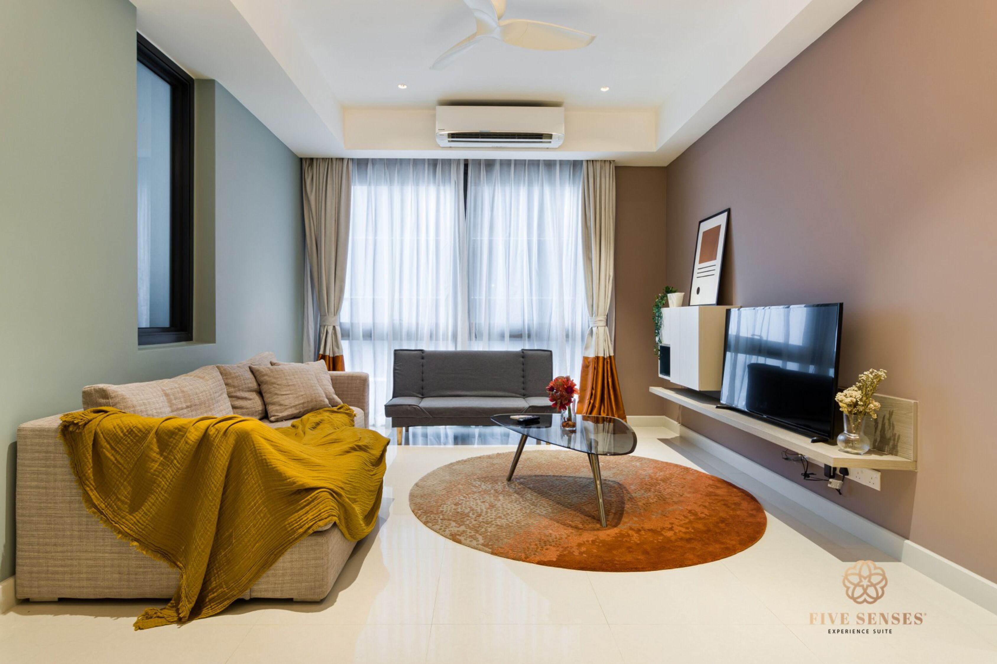 A modern living room with a sofa, a coffee table, a TV, and a ceiling fan.