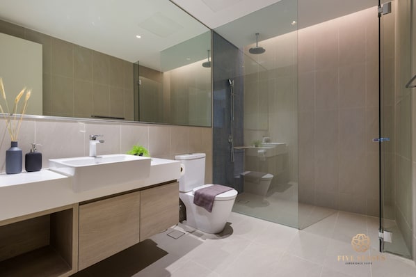 A modern bathroom with a glass shower enclosure, a white sink, and a toilet.