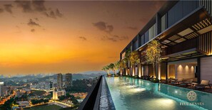 Ein modernes Hotel mit einem Dachpool im Infinity-Stil mit Blick auf eine Stadtlandschaft bei Sonnenuntergang.