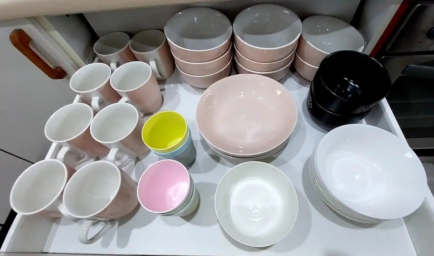 Diverse witte en roze keramieken borden en mokken op een tafel gerangschikt.