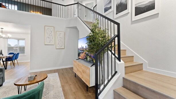 A spacious living area with a staircase, a dining area, and a view of the cityscape.
