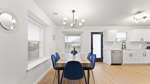 A modern kitchen with white cabinets, a wooden dining table, and blue chairs.