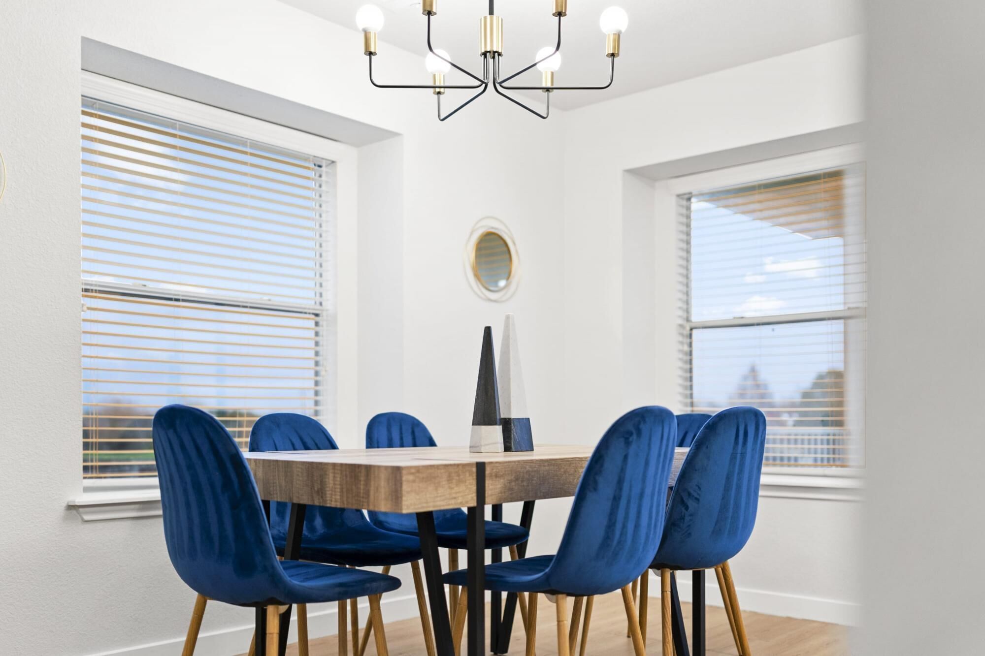 A dining area with a round wooden table surrounded by six blue chairs with wooden legs.