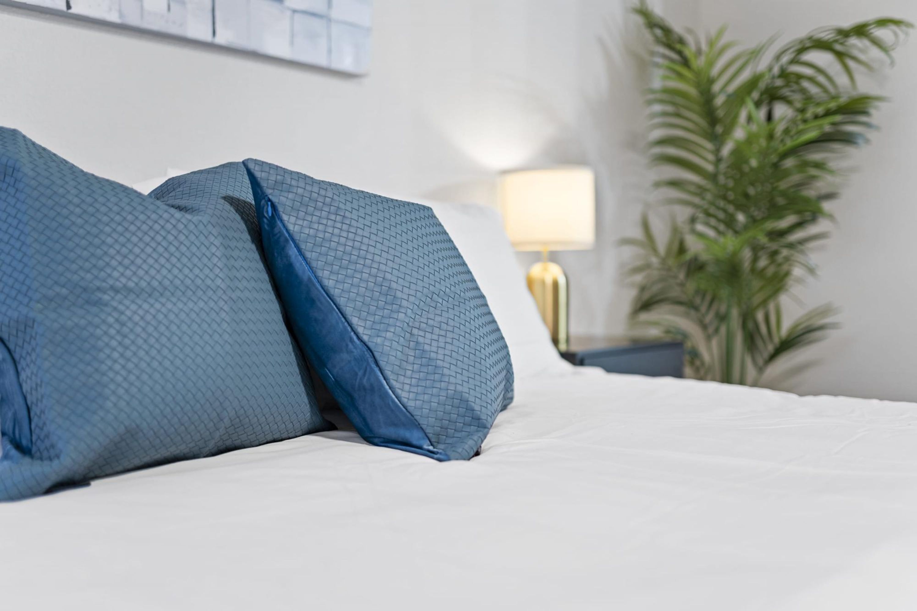 A bed with blue pillows and a white bedspread.