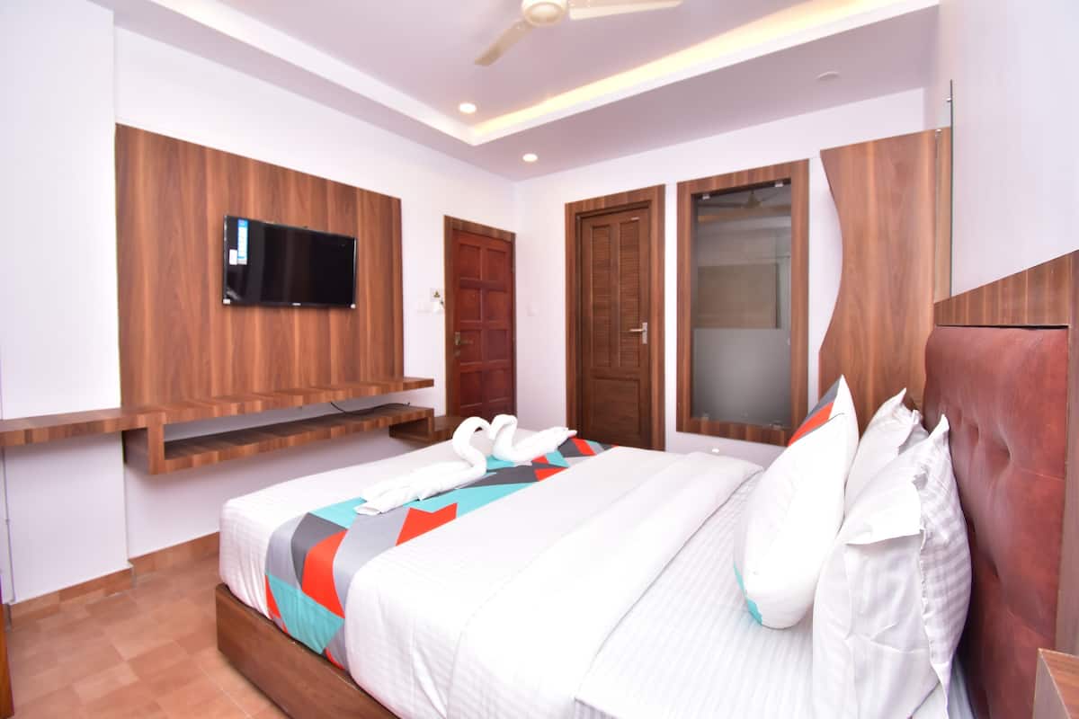 Una habitación de hotel moderna con cama, televisor montado, paneles de madera y armario.
