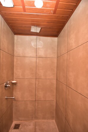 Ducha con techo de madera y paredes de azulejos.