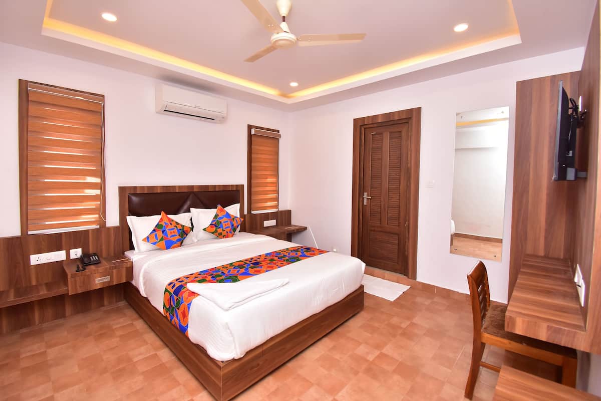 Una habitación de hotel moderna con una cama grande, cabecera de madera y un ventilador de techo.