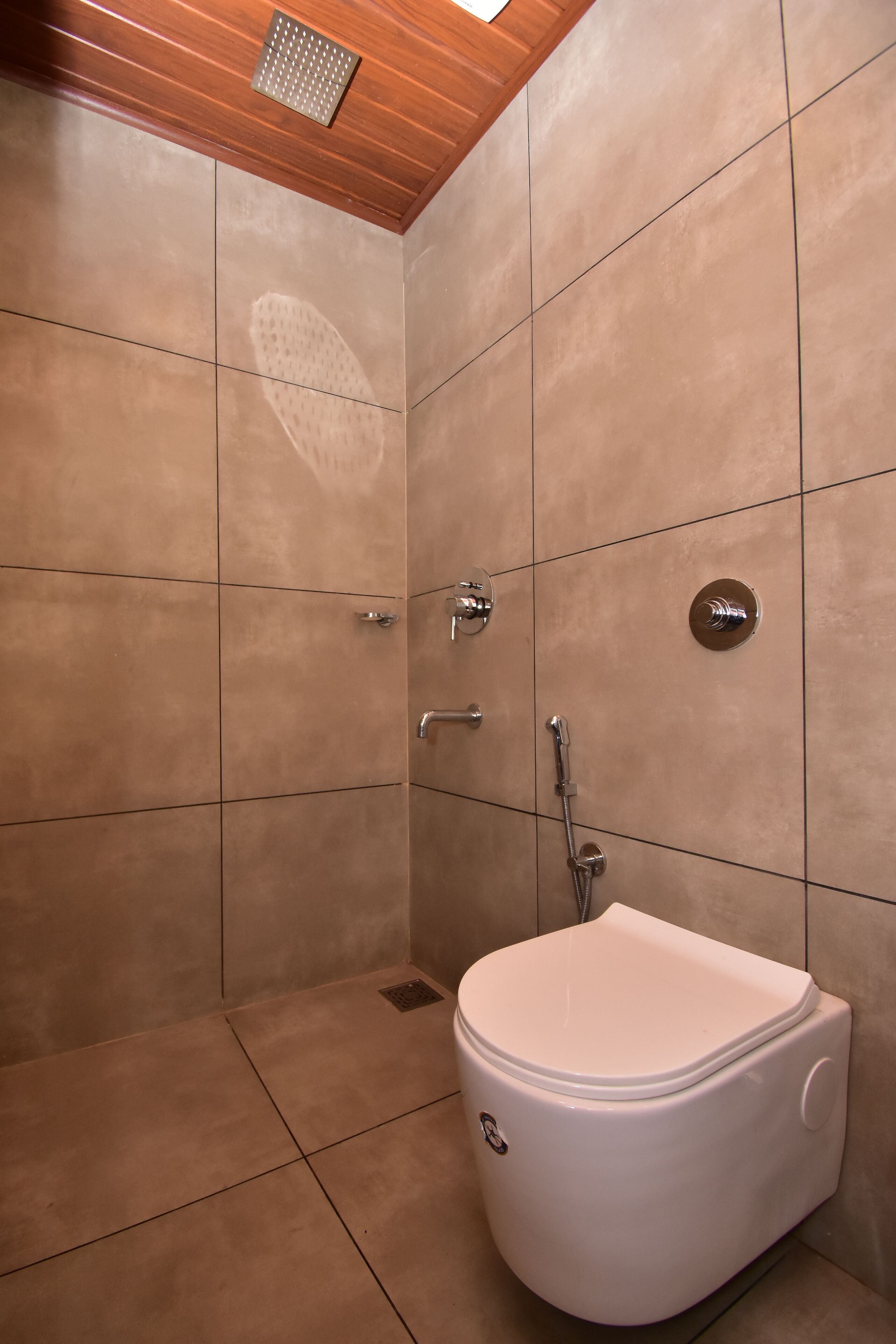 A modern bathroom with a white toilet, a shower, and a wooden ceiling.
