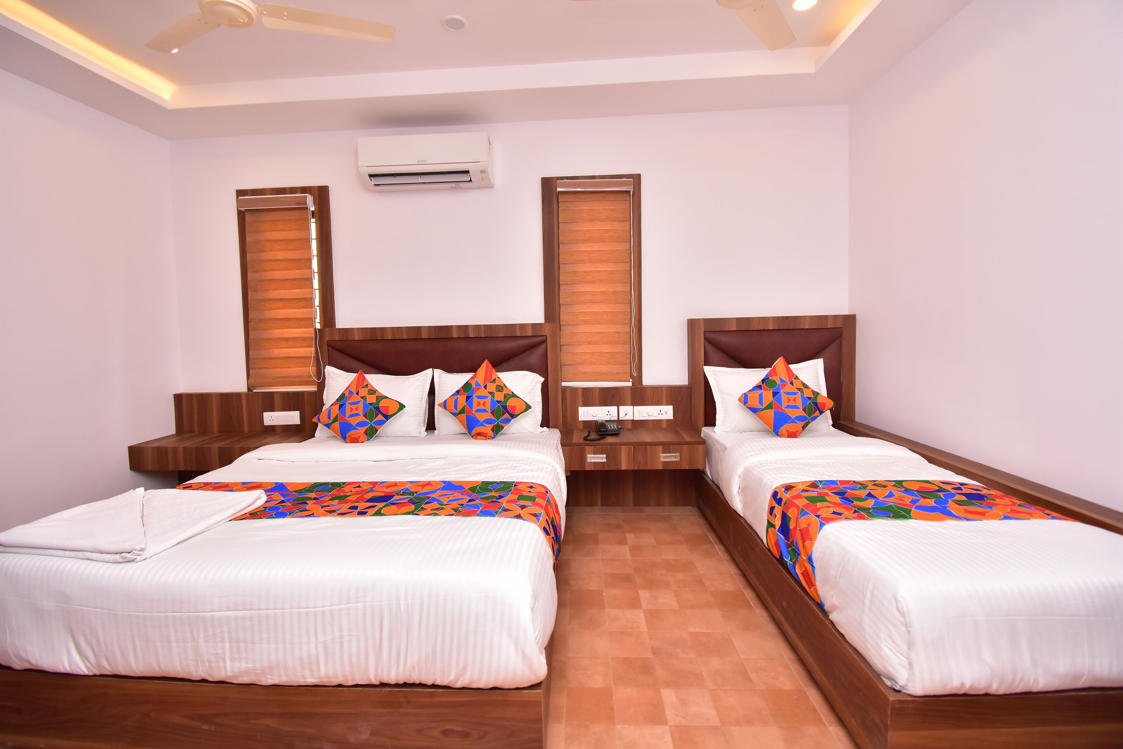 A hotel room with two beds, wooden headboards, white bedding, and a ceiling fan.