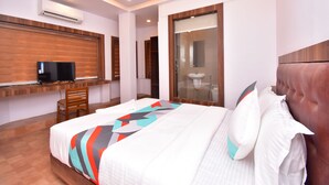 Een moderne hotelkamer met een groot bed, een bureau met een computer, een stoel en een badkamer met een douchecabine van glas.