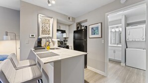 A modern kitchen with a central island, black refrigerator, and white cabinetry.